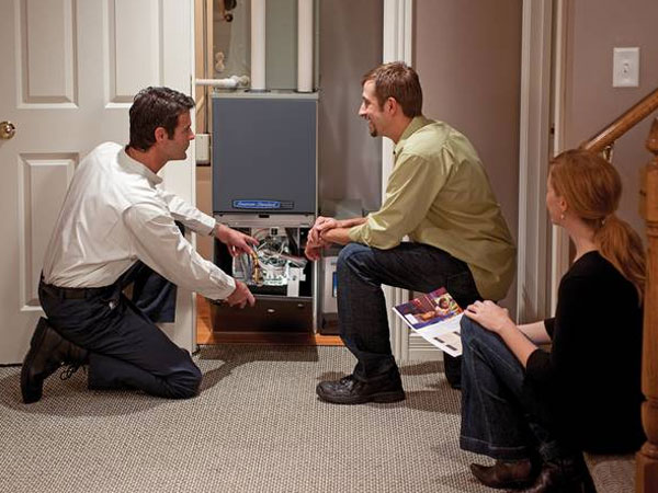 Technician explaining furnace maintenance to homeowners