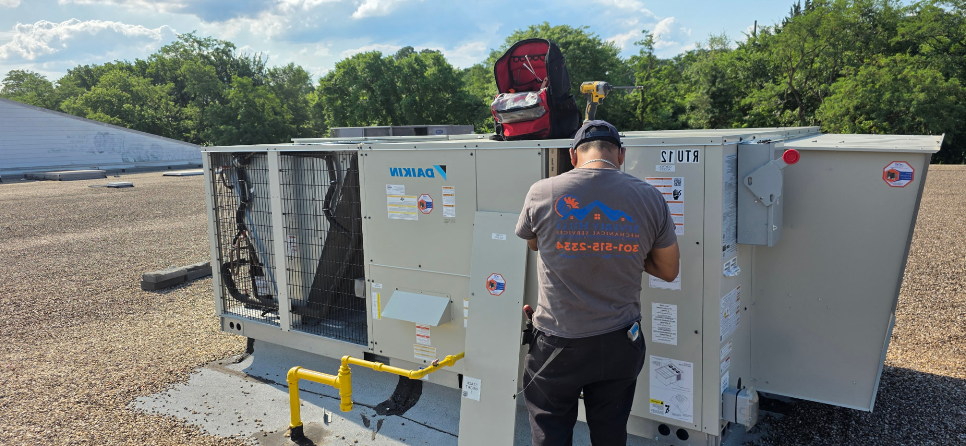 BHMS technician servicing a rooftop Daikin cooling unit